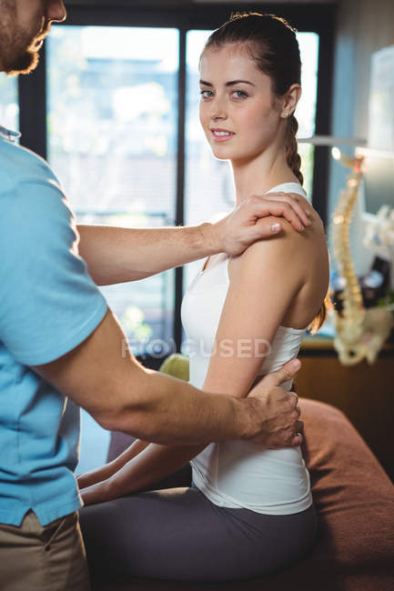 Fisioterapeuta masajeando espalda de paciente femenina en clínica - foto de stock