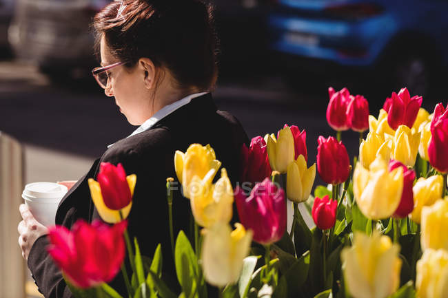 Jeune femme d'affaires debout près des fleurs — Photo de stock