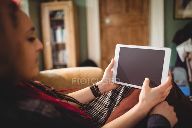 Jovem mulher usando tablet digital no sofá em casa — Fotografia de Stock