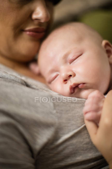 Close up of baby sleeping on mother in living room at home — Stock Photo
