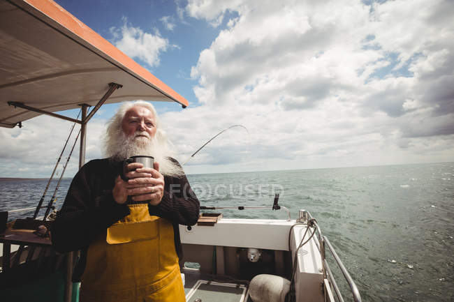 Thoughtful fisherman standing on boat with cup of coffee — Stock Photo