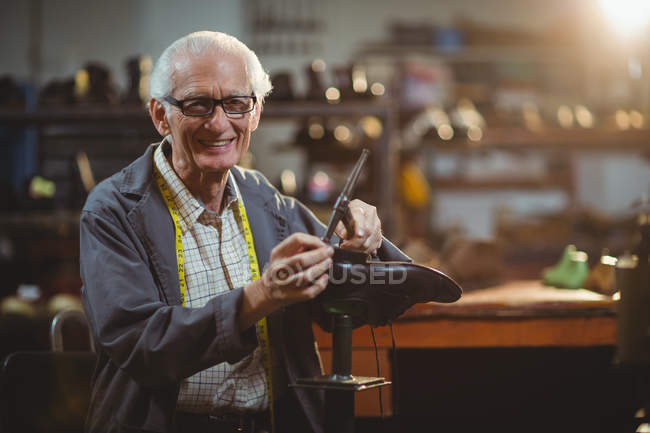 Smiling shoemaker hammering on a shoe in workshop — Stock Photo