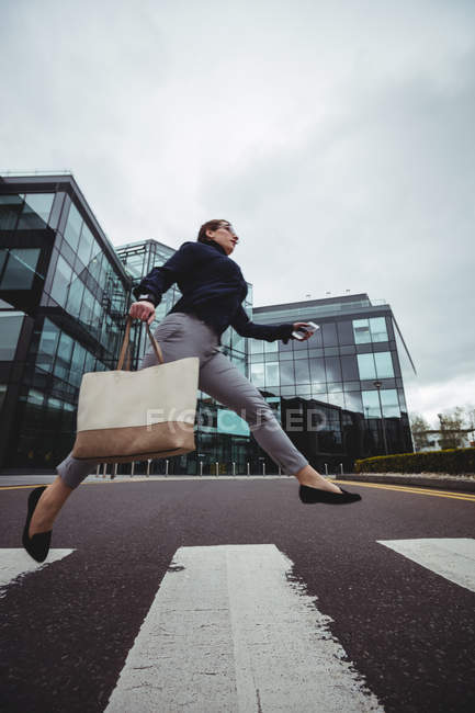 Comprimento total de empresária com saco correndo na estrada — Fotografia de Stock