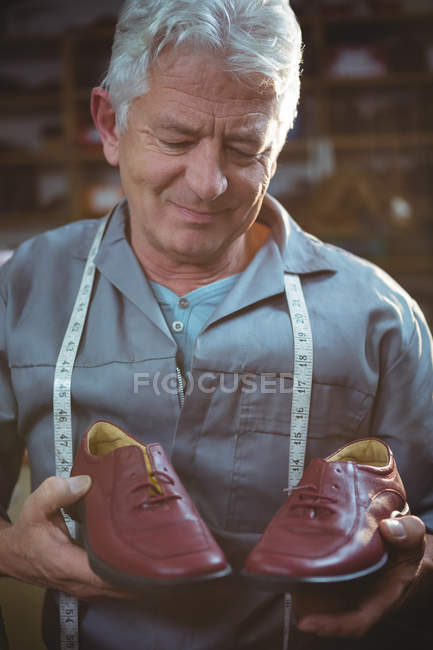 Обувщик, держащий пару обуви в мастерской — стоковое фото