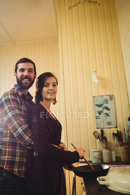 Embracing couple preparing food together in kitchen at home — Stock Photo
