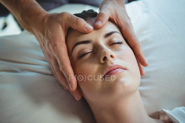 Physiothérapeute homme donnant un massage de la tête à une patiente en clinique — Photo de stock