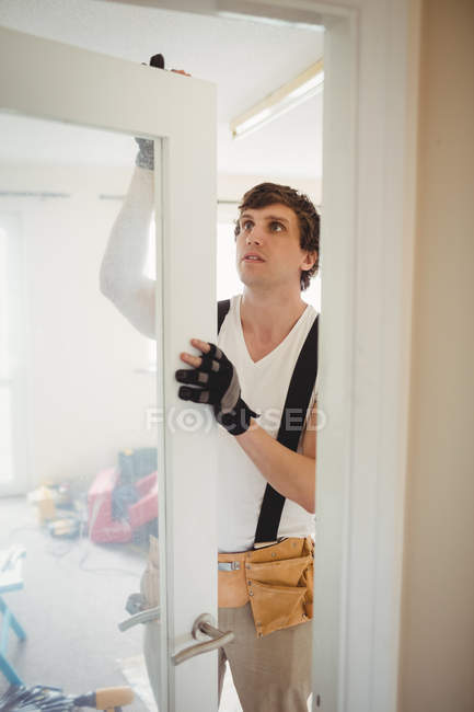Carpintero fijando puerta en casa - foto de stock