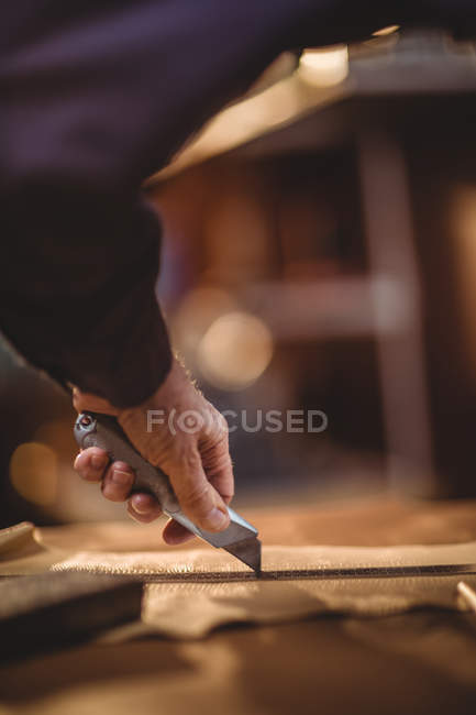 Hand des Schuhmachers, der in der Werkstatt ein Stück Leder schneidet — Stockfoto