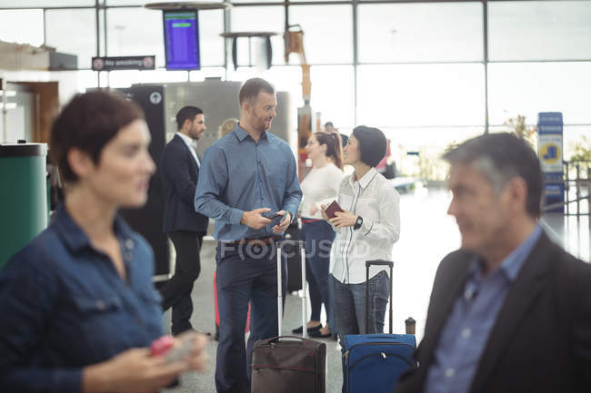 Empresários segurando cartão de embarque e usando telefone celular no terminal do aeroporto — Fotografia de Stock