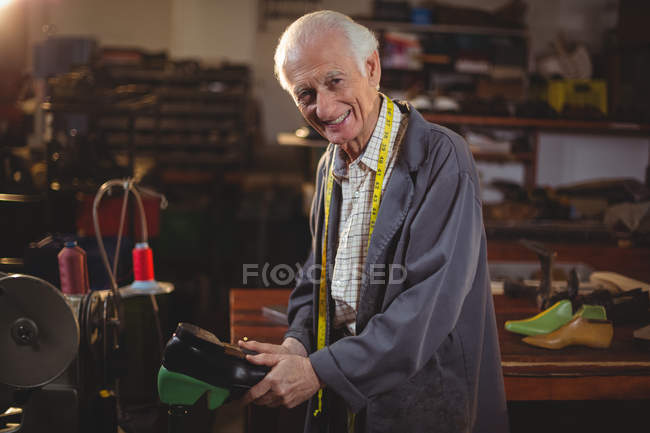 Старший сапожник чинит обувь в мастерской — стоковое фото