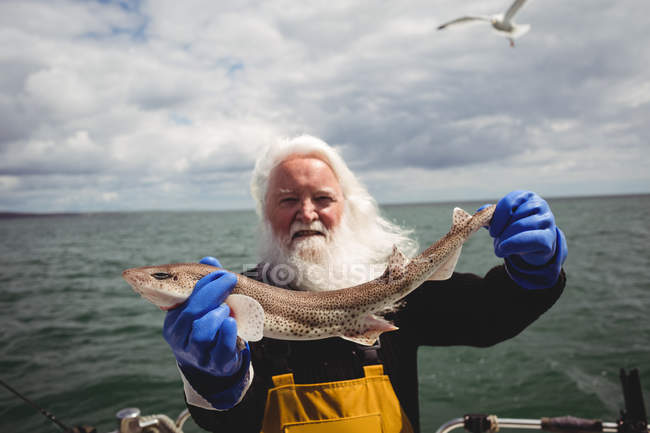 Ritratto di pescatore che mostra pesci su barca — Foto stock