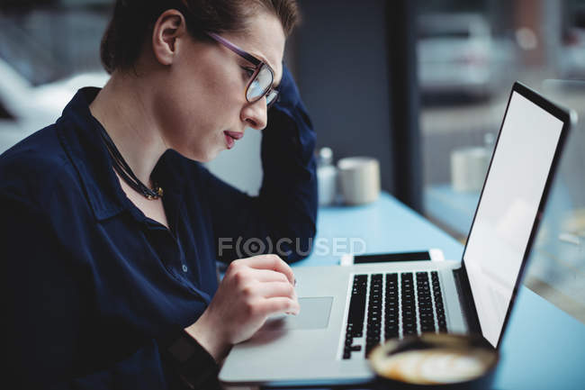 Jovem mulher trabalhando no laptop à mesa no café — Fotografia de Stock