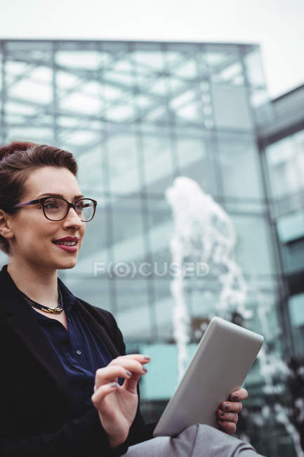 Smiling businesswoman holding digital tablet outside office building — Stock Photo