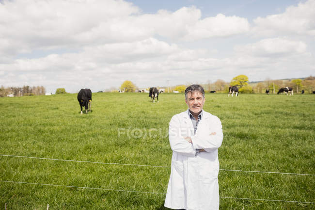 Retrato de veterinário confiante em pé no campo gramado contra o céu nublado — Fotografia de Stock