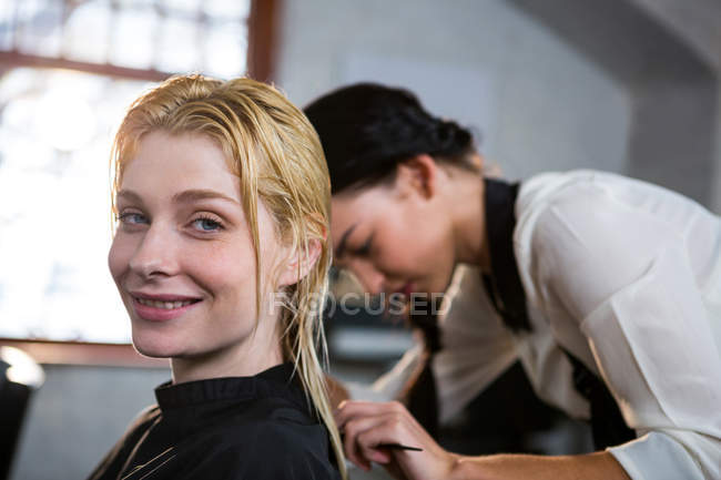 Перукар розчісує клієнтське волосся в салоні — стокове фото