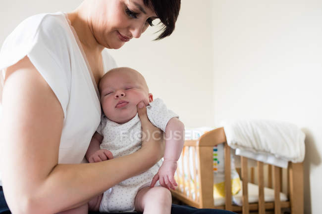 Mother holding baby while he sleeping in living room at home — Stock Photo