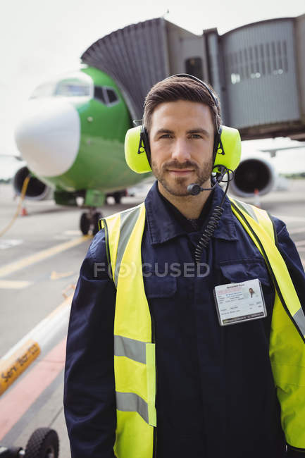 Retrato del personal de tierra del aeropuerto parado en la pista de aterrizaje en la terminal del aeropuerto - foto de stock