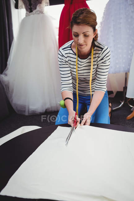Designer de moda feminina cortando tecido branco em estúdio — Fotografia de Stock