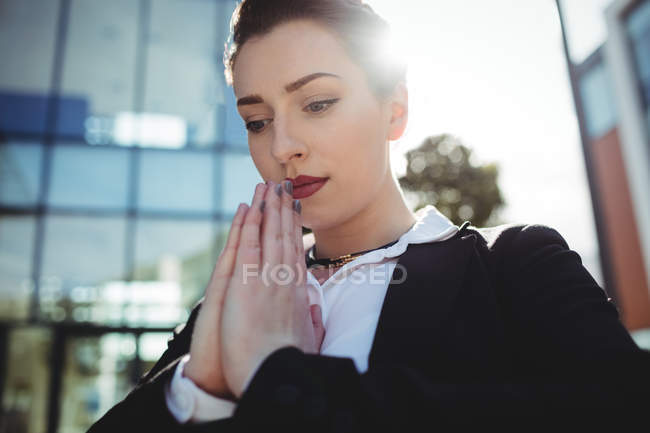 Schöne Geschäftsfrau mit gefalteten Händen beim Beten — Stockfoto