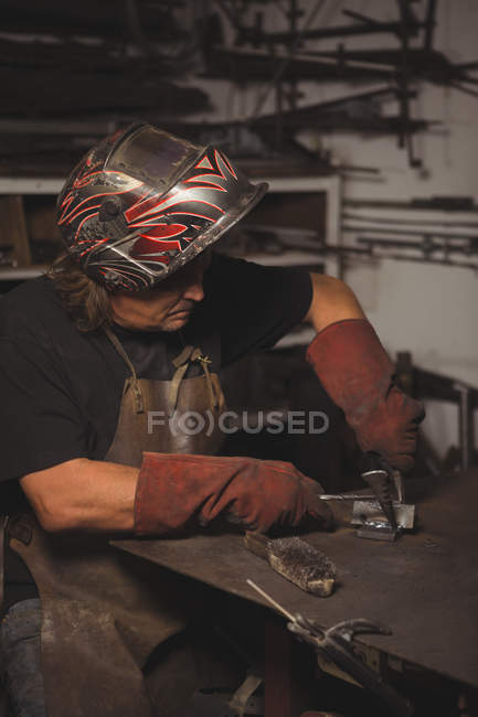 Blacksmith working on a metal piece in workshop — Stock Photo