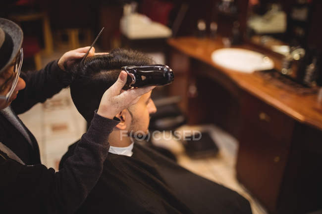 Mann lässt sich im Friseurladen Haare mit Trimmer schneiden — Stockfoto