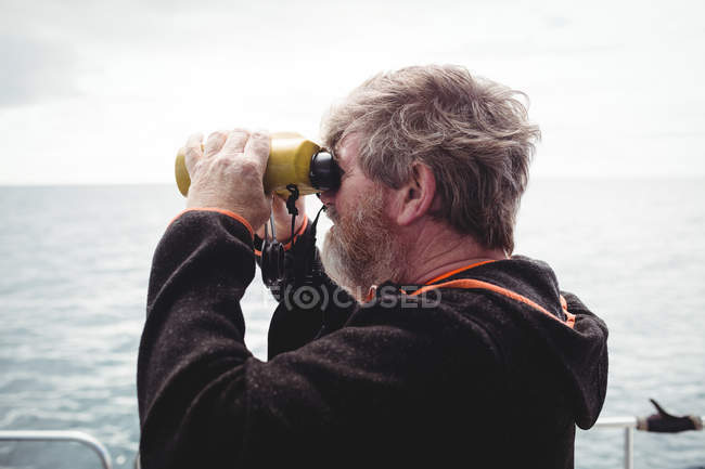 Pescador mirando a través de binoculares desde el barco - foto de stock