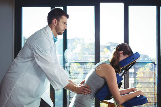 Fisioterapeuta dando masaje de espalda a la paciente femenina en la clínica - foto de stock