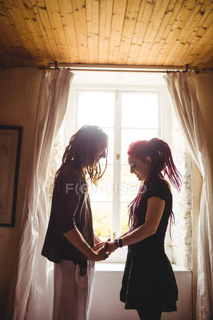 Молода пара тримає руки проти вікна вдома — стокове фото
