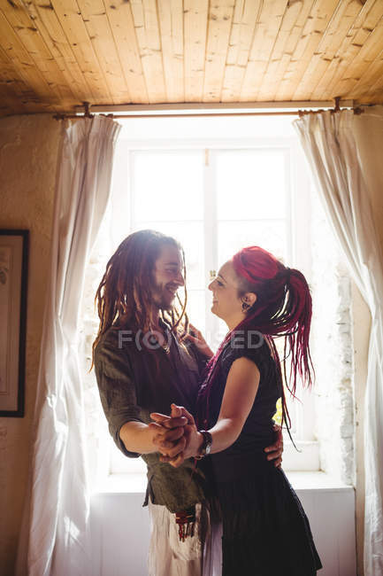 Young couple dancing against window at home — Stock Photo