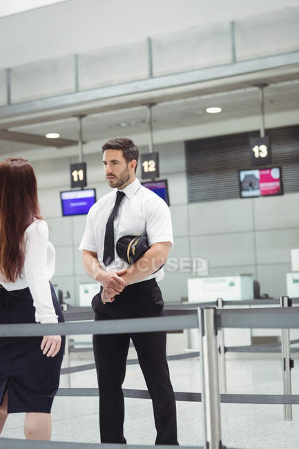Pilot and flight attendant interacting with each other in airport terminal — Stock Photo