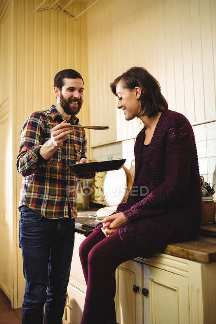 Mann füttert Frau in Küche zu Hause mit Lebensmitteln — Stockfoto