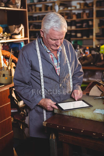 Shoemaker using digital tablet in workshop interior — Stock Photo