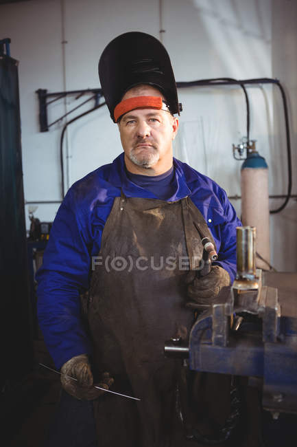 Retrato de soldador que sostiene la máquina de soldadura en el taller - foto de stock