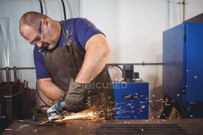 Beau soudeur coupe métal avec outil électrique en atelier — Photo de stock
