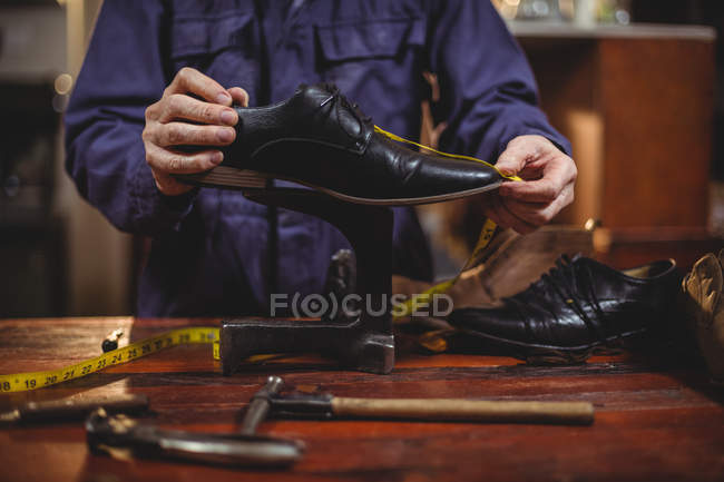 Средняя часть сапожника-мужчины ремонтирует обувь в мастерской — стоковое фото