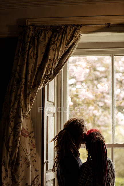 Романтическая пара, стоящая у окна дома — стоковое фото