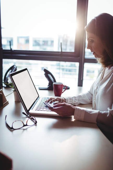 Geschäftsfrau mit Handy und Laptop im Büro — Stockfoto
