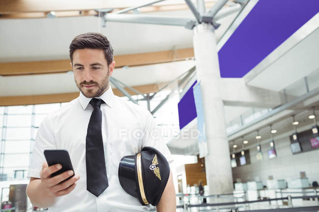Pilote utilisant un téléphone portable dans le terminal de l'aéroport — Photo de stock
