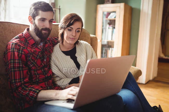 Giovane coppia utilizzando il computer portatile in soggiorno a casa — Foto stock
