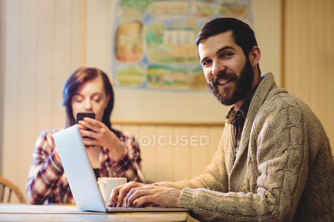 Couple using laptop and mobile phone at home — Stock Photo