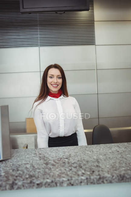 Portrait of airline check-in attendant at airport check-in counter — Stock Photo