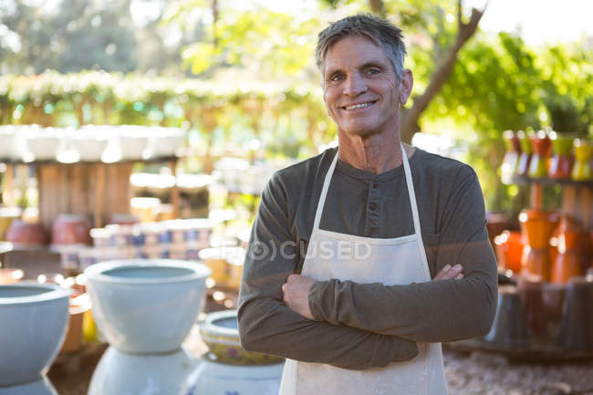 Happy male potter standing with arms crossed in pottery workshop — Stock Photo
