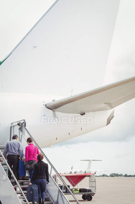Пасажири піднімаються по сходах і входять у літак в аеропорту — стокове фото