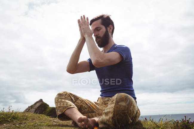 Человек, занимающийся йогой на скале — стоковое фото