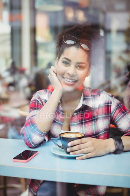 Retrato de una joven sonriente sentada en el restaurante - foto de stock