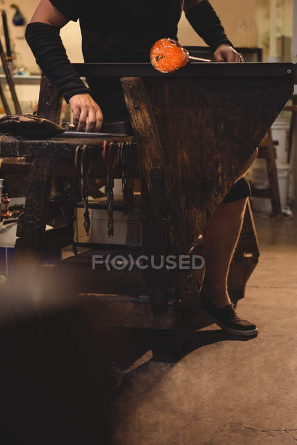 Обрезанное изображение стеклодува, формирующего расплавленное стекло на стекольном заводе — стоковое фото