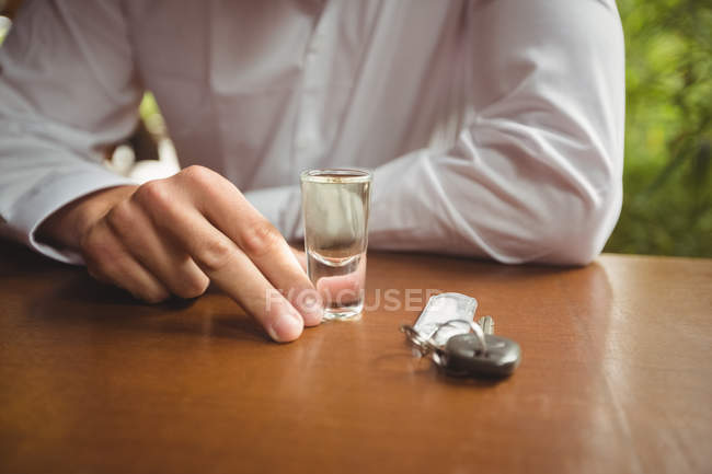 Partie médiane de l'homme tenant un verre de tequila tiré dans le comptoir du bar au bar — Photo de stock