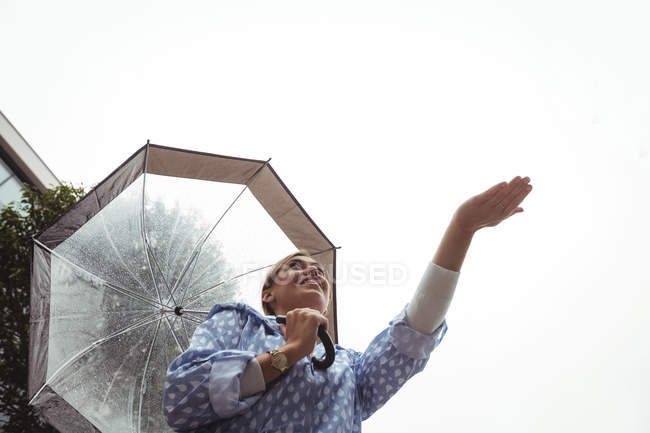 Niedrigwinkel-Ansicht einer schönen Frau, die während der Regenzeit Regen genießt — Stockfoto