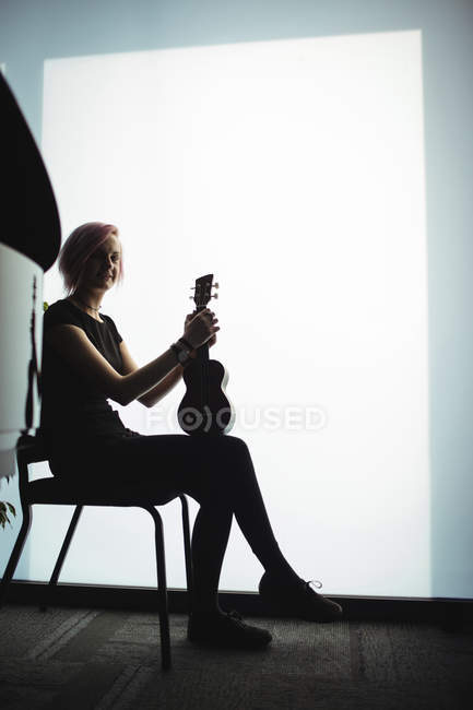 Портрет женщины, сидящей с гитарой в музыкальной школе — стоковое фото