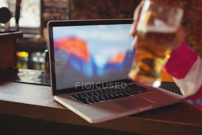 Man holding a glass of beer at bar counter — Stock Photo